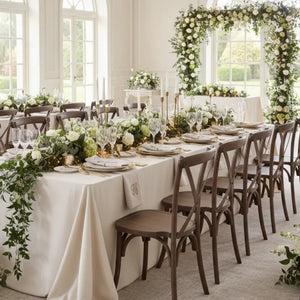 Elegant wedding reception setup with tables, chairs, and floral decorations in a bright room.
